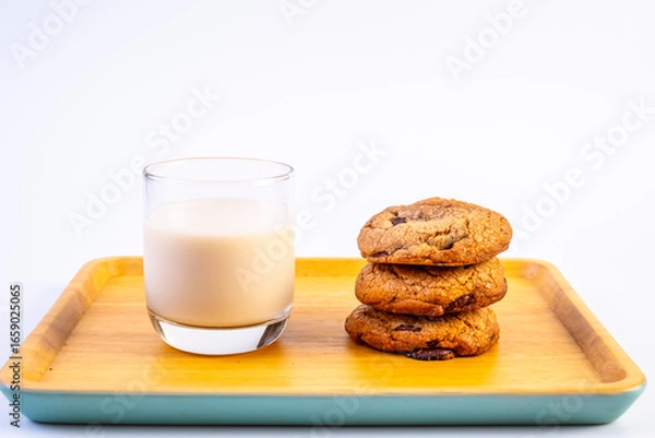 Fototapeta Stack of Dark Chocolate cookies with a cup of milk on wooden plate and on white background