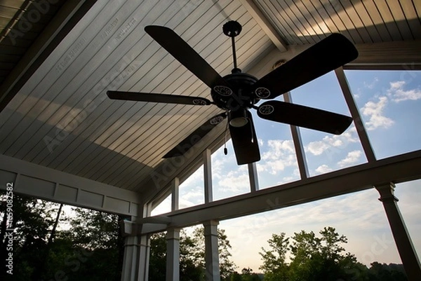 Fototapeta Low-Angle View of a Six-Blade Ceiling Fan in a Covered Porch with a View of...