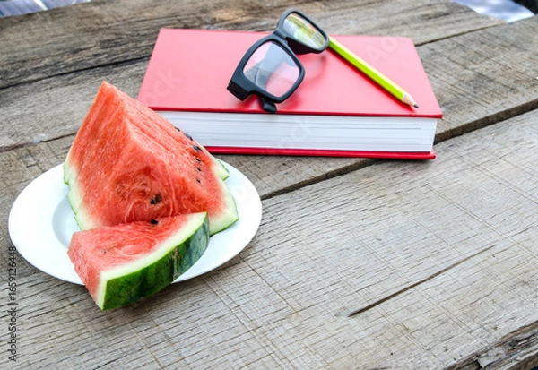 Fototapeta Watermelon with red book on wooden table