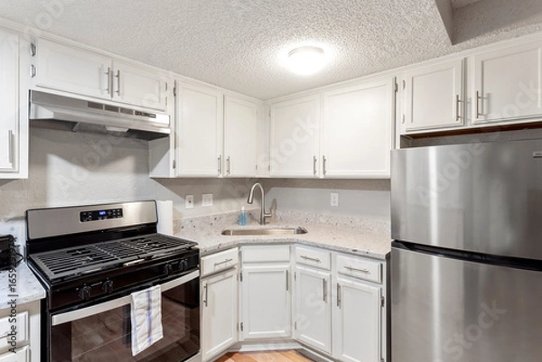 Fototapeta Bright living room interior in modern apartment with large windows
Clean white kitchen with stainless appliances in contemporary condo