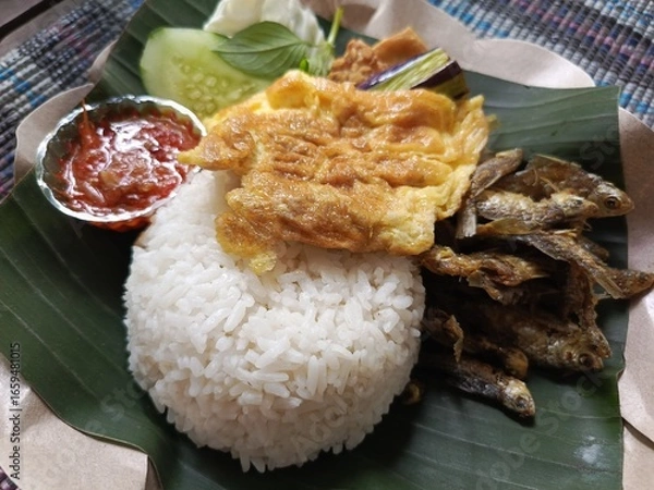 Fototapeta The traditional dish penyetan wader and Chicken refers to wader fish that is fried crispy and then crushed with spicy chili sauce, and traditional woven fish as a serving method or garnish. 