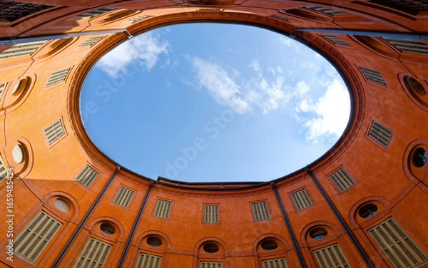 Fototapeta Rotonda Foschini, elliptical courtyard located in Ferrara, Italy. The courtyard's design creates a sense of symmetry and harmony, with the open sky visible above, adding to its enchanting atmosphere.
