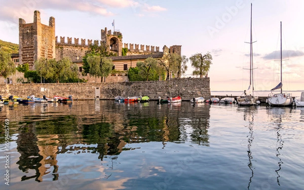 Fototapeta The Scaligero Castle by the small port of Torri del Benaco, Garda lake, Italy. An impressive medieval structure with walls and towers, reflecting its historical significance and architectural style.