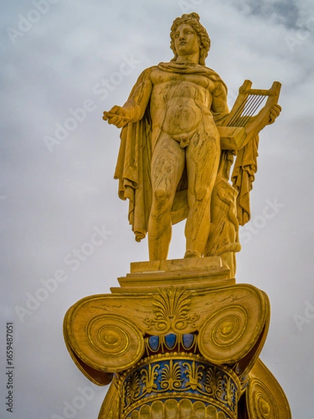 Fototapeta A majestic marble statue of Apollo, the ancient Greek god of music and fine arts, standing elegantly on a column while holding a lyre, symbolizing harmony and artistic mastery.