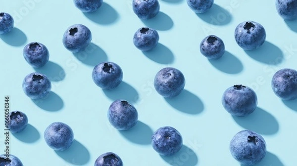 Fototapeta A uniform pattern of plump fresh blueberries evenly spaced in diagonal rows on a smooth pastel blue background, showcasing natural berry texture in a minimalist flat lay composition.
