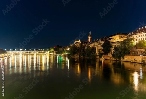 Fototapeta A night, long exposure, panorama of the Rhine in Basel with the brightly lit bridge and cathedral in the background.