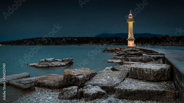 Obraz A wide angle shot of a lit lighthouse in Lake Geneva, Switzerland during early evening