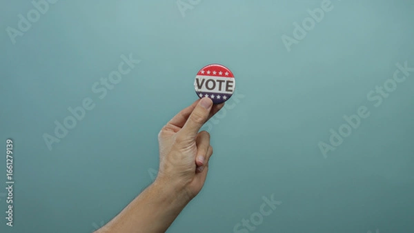 Obraz Hand holding vote button on blue background, showing political engagement and democracy, emphasizing election participation by caucasian man.