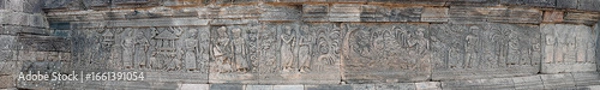 Fototapeta A panoramic view of ancient stone relief carvings depicting figures on architectural walls