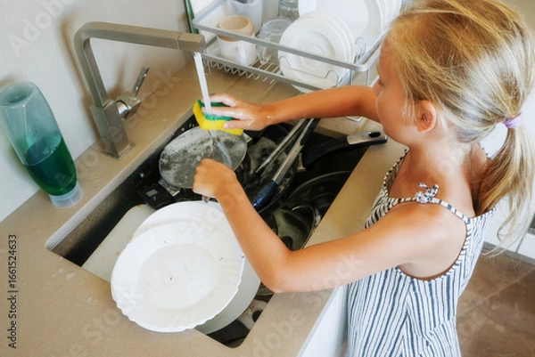 Obraz Girl scrubbing fork with sponge above kitchen sink with soapy water