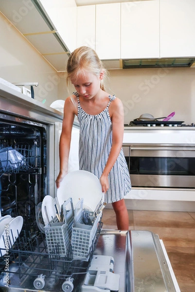 Obraz Girl loading dirty dish into open dishwasher in modern kitchen
