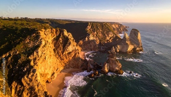 Fototapeta Aerial View of Rocky Coastline at Sunset with Waves Crashing on Shore