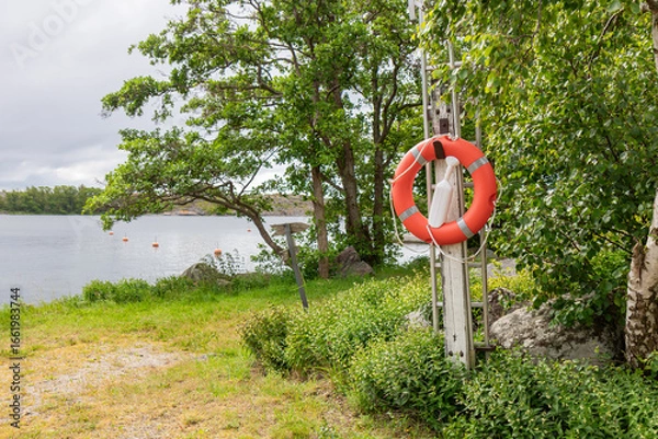 Fototapeta Close-up of lifebuoy at Finnish marina on the Baltic Sea. Safety equipment ready for emergency use, symbol of SOS, rescue, and maritime security in nautical environment