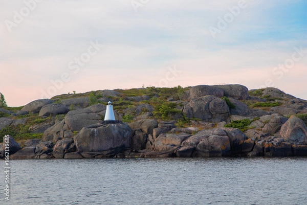 Fototapeta Marine channel marker on coastal rocks, indicating the edge of the channel. Coastal navigation aid in Baltic sea, highlighting safety, marine guidance, and rocky shoreline