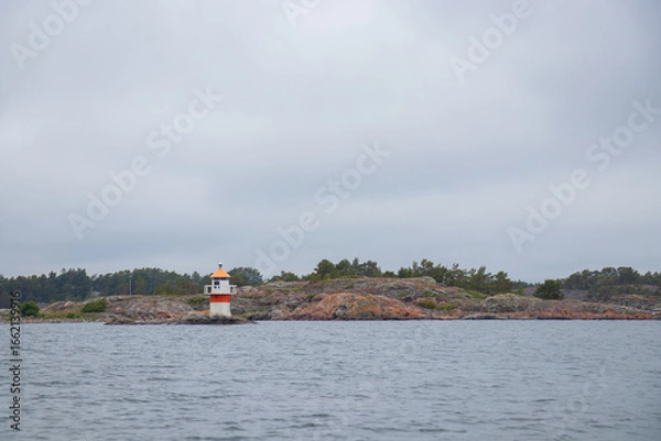 Fototapeta Marine channel marker on coastal rocks, indicating the edge of the channel. Coastal navigation aid in Baltic sea, highlighting safety, marine guidance, and rocky shoreline