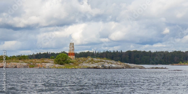 Fototapeta Marine marker made of stacked stones on the shore. Coastal navigation aid in Baltic sea, marking channel edges, blending natural materials with maritime safety in rocky environment