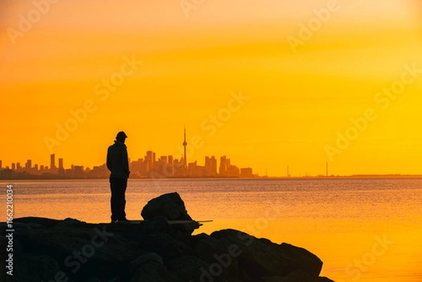 Fototapeta Toronto skyline in the morning. Silhouette figure of a man enjoying the Toronto sunrise