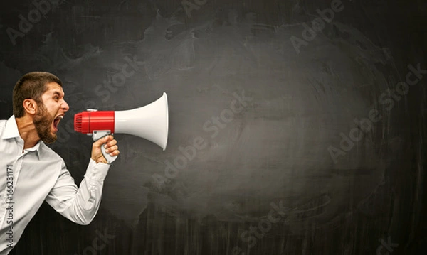 Obraz Zły młody człowiek krzyczy megafon