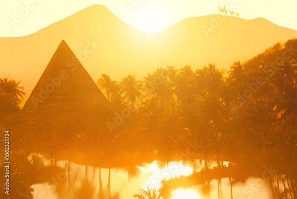 Fototapeta A silhouette of a pyramid against a golden sunset, surrounded by palm trees and a reflective water body, with mountains in the background