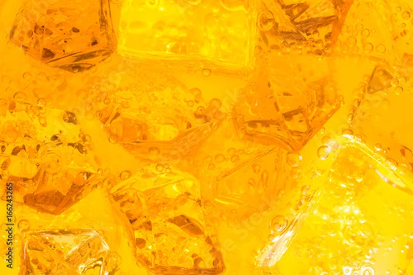 Fototapeta Close-up of ice cubes in drink or orange juice