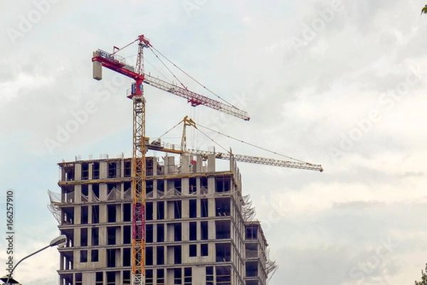 Fototapeta Monolithic concrete frame of the building and the red crane