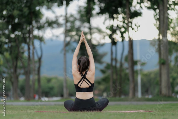 Fototapeta Calm and focused woman exercising yoga in a public garden, embracing relaxation and harmony with nature.