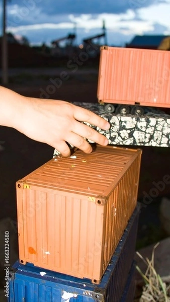 Obraz Hand reaching for stacked shipping containers