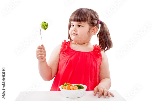 Fototapeta How to teach children to eat healthy food. Girl with broccoli isolated on white background