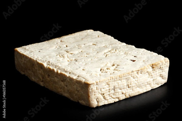 Fototapeta Single block of lightly smoked tofu isolated on black.