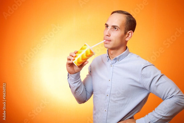 Fototapeta young man drinking a cocktail through a straw