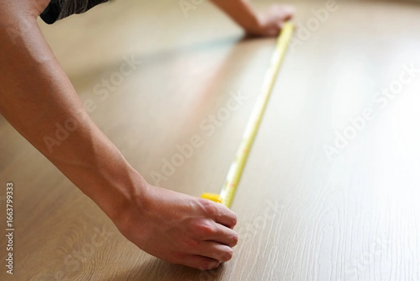 Obraz フローリングの床をメジャーで測定している男性　引越し、リフォームのイメージ