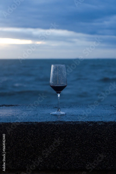 Obraz A single glass of chilled white wine on a table by the blue ocean and beach