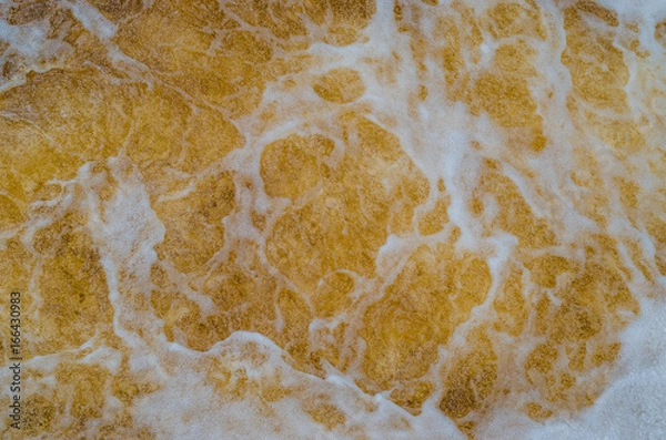 Fototapeta Water with foam. Yellow shade like gold or beer. Abstraction for background. Movement of colored water.