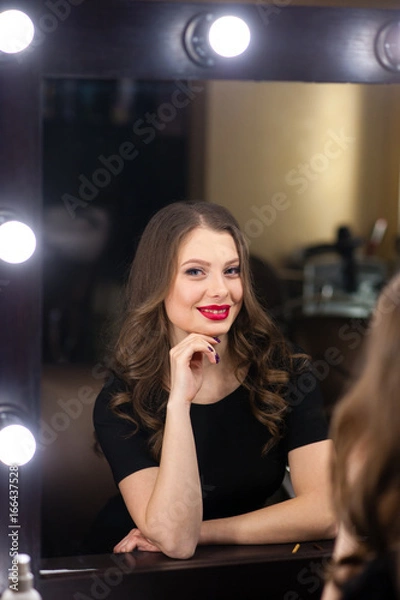 Fototapeta Beautiful girl smiling and looking in the mirror