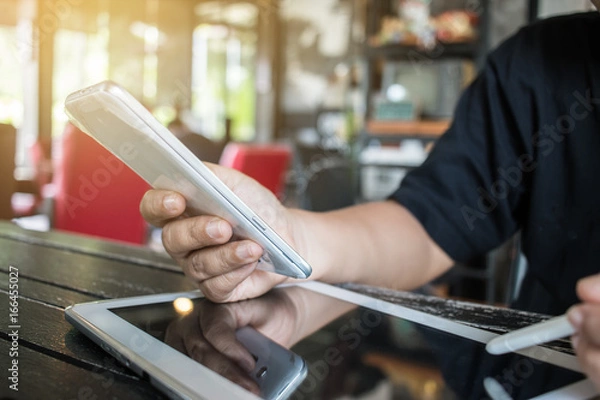 Fototapeta Businesswoman holds a white smartphone or smart device on her right hand and a stylus pen on the left hand, chats with friends via an instant messaging app over the public internet. Internet concept.
