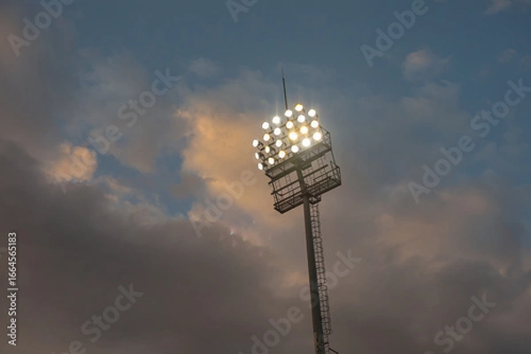 Fototapeta Football Stadium Floodlights at Sunset with Clouds – Concept of Soccer and Sport Atmosphere