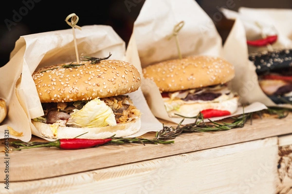 Fototapeta Fresh hamburgers wrapped in paper on a wooden table