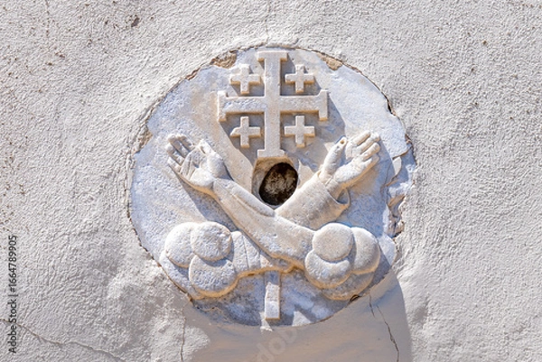 Fototapeta The Jerusalem Cross or Crusader Cross with two hands on each side of the cross representing Jesus and St. Francis of Assisi carved in stone on Saint John's Baptist Church in the old city of Acre, Akko