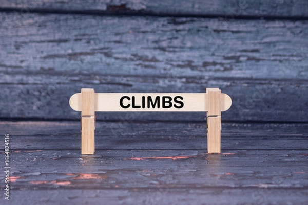 Fototapeta Climbs symbol. Wooden stick fastened by Clothespins, A lightly orange toned grunge wooden background. Business and Climbs concept with copy space