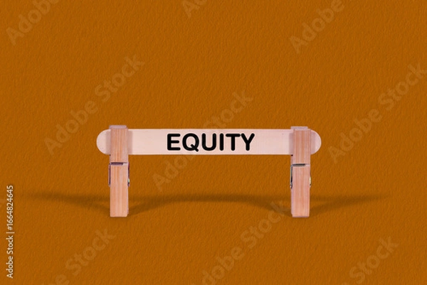 Fototapeta Equity symbol. Wooden stick tightened by Clothespins, beautiful Orange color Backdrop. Business and Equity concept with copy space