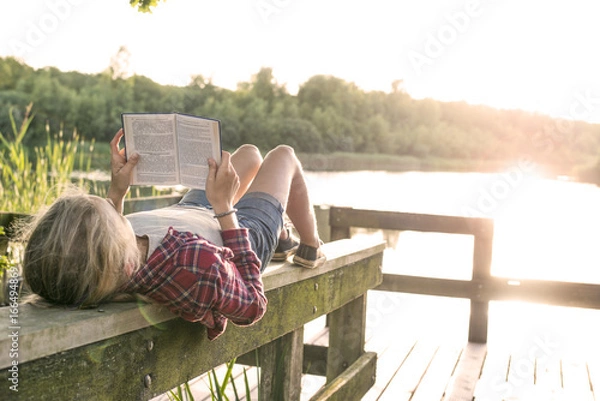 Fototapeta girl reading a book in the sun
