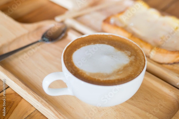 Obraz Hot drink coffee with white foam in the white cup. wooden tray and table with bread slice toast
