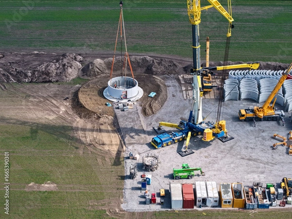 Fototapeta Large heavy-duty crane sets first parts for the tower of a wind turbine, building construction, wind energy, wind turbine, construction, crane, energy transition, sustainability, energy, renewable