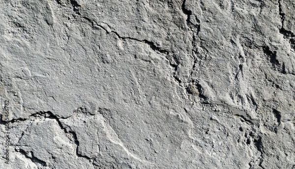 Fototapeta A close-up view of a weathered gray stone surface, showing intricate patterns of cracks and texture.