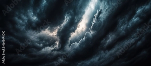 Fototapeta Dramatic view of swirling, dark storm clouds with bright patches of light.