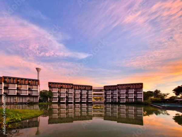 Fototapeta A modern luxury hotel resort building and the evening sky along the river