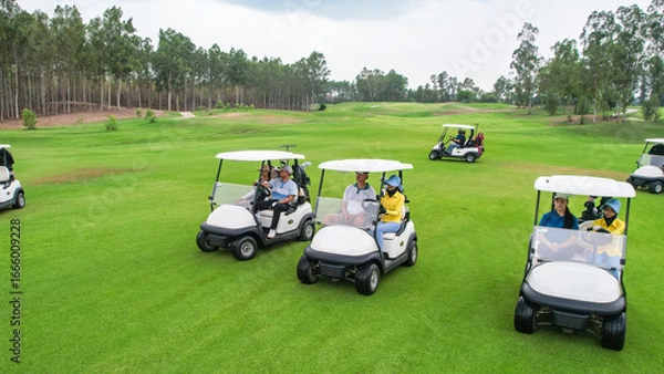Fototapeta Drone view of group of golfers riding together in golf cart on course. 