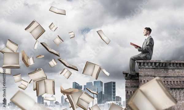 Fototapeta Man on roof reading book and many of them flying in air