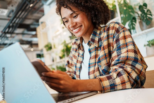 Fototapeta A Smiling Woman Actively Working on Her Laptop in a Cozy and Inviting Indoor Space