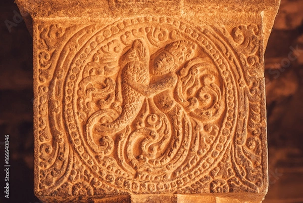 Fototapeta Silhouette of woman and big fish on historical stone column in India. Traditional patterns of Hindu temples, made in 7th century in Karnataka state.